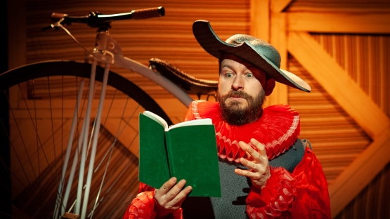 Un home vestido do Quixote lendo un libro, un momento da obra "Quixote" da compañía Pedras de Cartón